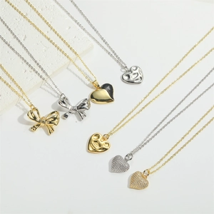 Close-up of gold and silver necklaces with black enamel hearts and bow pendants