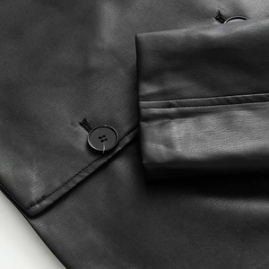 Detailed macro view of black faux leather jacket cuff with matching resin button and fine stitching