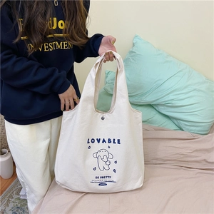 Détail du sac cabas en toile crème avec imprimé chien bleu et bouton pression métal