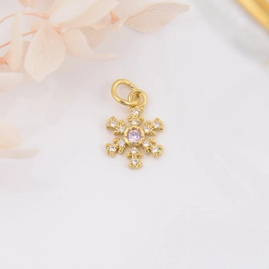 Macro shot of 18k gold plated snowflake pendant with pink zircon for DIY jewelry