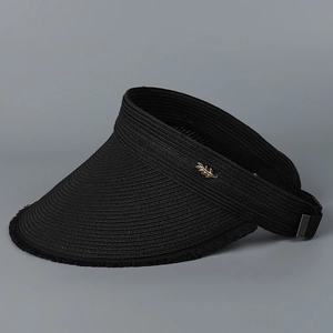 Detail of black straw open top sun hat featuring a gold leaf metallic buckle accessory