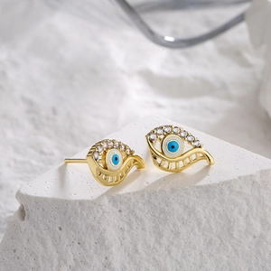 18K gold plated evil eye stud earrings with blue zircon on a white stone pedestal