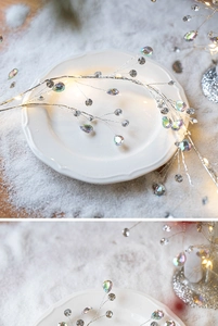 Silver lighted branch with iridescent crystal beads on a white tray with snow