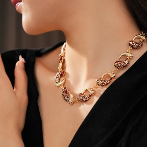 Close-up of vintage golden necklace with red enamel and crystals on a model neck