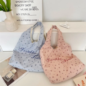 Close-up of floral canvas tote bags with blue and pink patterns and embroidered text