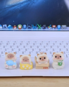 Set of four cute miniature resin cat figurines displayed on a modern office desk setup