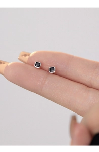 Macro shot of minimalist silver square earrings with black gemstone inlays for women
