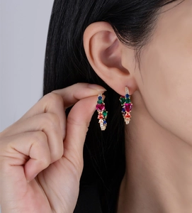 Close-up of heart-shaped red stone earring with colorful pavé zircons on model ear