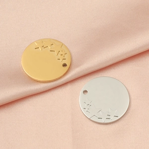 Close-up of gold and silver star engraved stainless steel pendants on pink silk