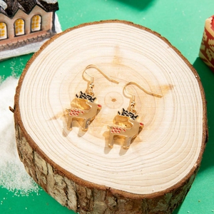 Close-up of golden reindeer earrings with red spots on a festive wood background