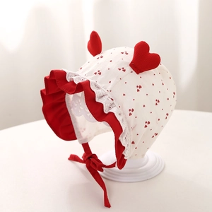 Dettaglio cappello neonato con cuori rossi, volant in pizzo e decorazioni 3D a cuore rosso