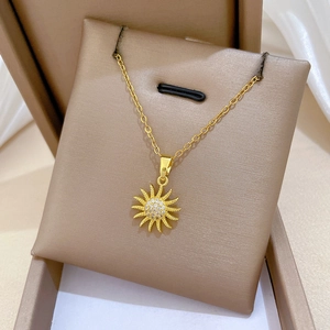 Detail of a rotating gold sun flower necklace with shimmering crystals in a jewelry box