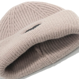 Close-up of ribbed knit texture and logo patch on beige winter beanie hat
