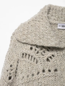 Detail of chunky knit cardigan featuring hollow-out patterns and thick lapel collar
