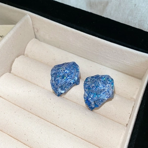 Macro shot of unique blue resin earrings with sparkling texture in jewelry storage box