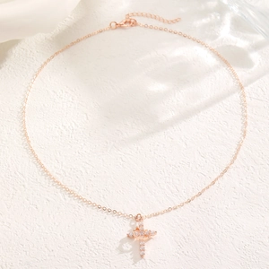 Detail shot of rose gold cross necklace with sparkling crystals on textured white background