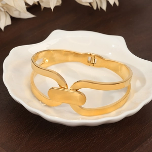 Minimalist gold hollow geometric bangle with layered double-ring design on white tray