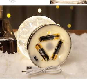 Detail of Christmas snow globe power base showing USB cable and AA battery compartment