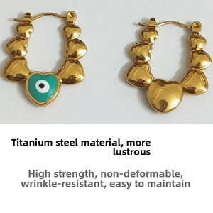 Detail of gold titanium steel heart earrings with green evil eye and clip-on buckle