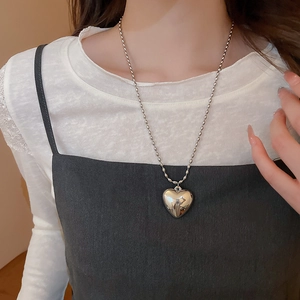 Detailed close-up of a silver heart pendant on a stylish bead chain necklace for women