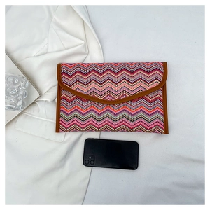 Detailed view of colorful woven straw envelope clutch bag with leather trim and phone