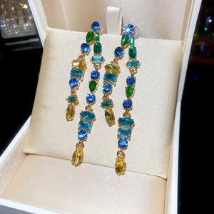 Macro shot of colorful gemstone tassel earrings in a golden frame within a silk gift box