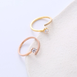 Minimalist zircon open rings in gold and rose gold on a white ceramic base