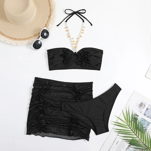 Dettaglio del bikini nero a tre pezzi con catena dorata e gonna a rete coordinata
