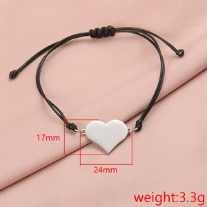 Detail view of mirror finish silver heart charm on black woven bracelet over pink silk