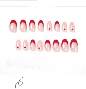 Detail view of red and pink French press-on nails with heart patterns and oval shape