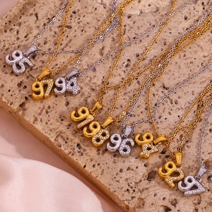 Macro shot of 18K gold and silver year necklaces with rhinestones on silk and stone background