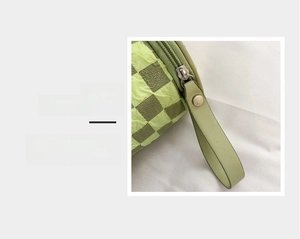 Detail magnification of smooth metal zipper on light green checkered cylinder bag