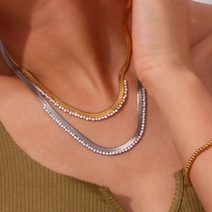 Macro detail of gold and silver herringbone chains with zircon stones on model