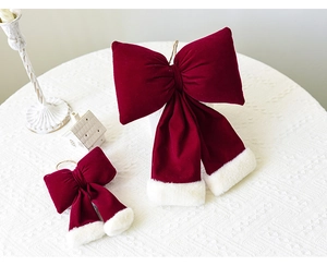 Detail of red velvet Christmas bows with plush white trim and hanging ropes in two sizes