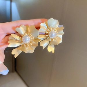 Detailed view of golden flower earrings with matte petals and centered pearl detail