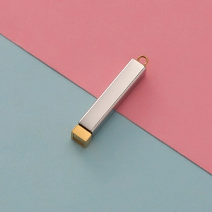Close-up of a rectangular steel cylinder pendant with a gold and silver bicolor finish