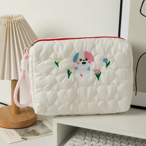 Detail of white heart-quilted cosmetic bag with cute dog embroidery and red zipper