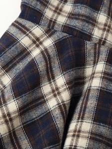 Close-up of flannel plaid fabric detail with navy, brown, and beige textured weaving