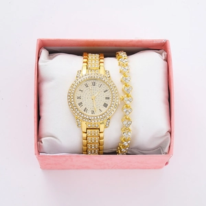 Macro view of gold iced-out watch and heart bracelet set inside a pink luxury gift box
