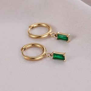 Minimalist gold hoop earrings with rectangular green zircon pendants on purple silk cloth