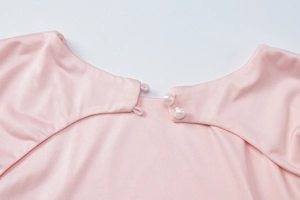 Detail of pink knitted dress neck with elegant faux pearl buttons and elastic loops