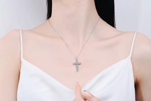 Detail of silver cross necklace with clear moissanite pendant on female model