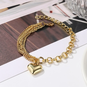 Detail view of gold wheat and link chain bracelet featuring a polished heart pendant