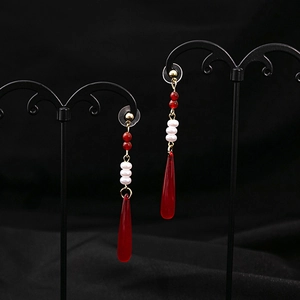 Detailed close-up of dark red teardrop tassel earrings with vintage beads and gold finish