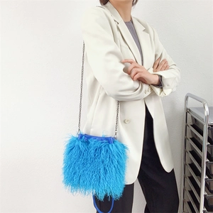 Detailed shot of bright blue faux sheep fur bucket bag with metal chain strap and drawstring