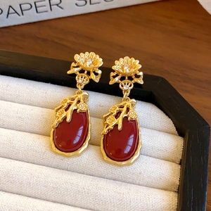 Detail of red teardrop earrings with golden plum blossom patterns and clear crystals