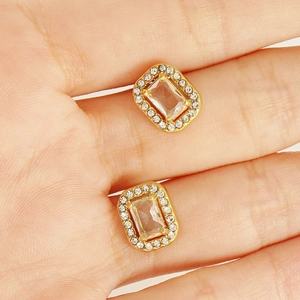 Macro detail of gold vintage stud earrings with rectangular zircon and diamond halo
