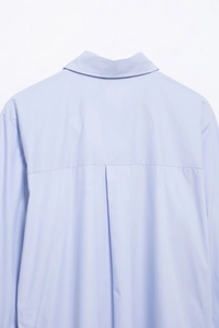 Detail view of the back yoke and central box pleat on a light blue striped casual shirt