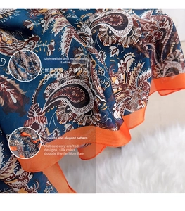 Detail of navy blue paisley printed silk scarf with vibrant orange chiffon hem borders