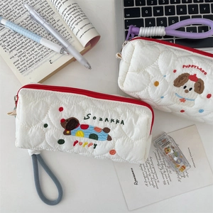 Detailed view of two cute quilted puppy embroidered pencil cases on a study desk